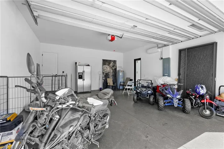 Garage featuring stainless steel fridge with ice dispenser, electric panel, a garage door opener, and water heater