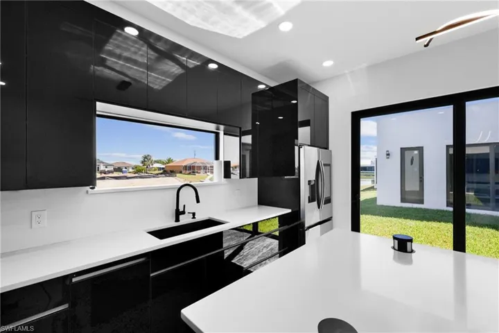 Kitchen with dark cabinets, modern cabinets, a sink, light countertops, and recessed lighting