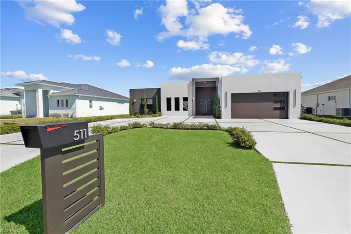 Contemporary home with a garage, driveway, a front yard, stucco siding, and central AC