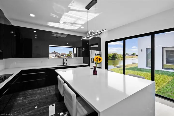 Kitchen with dark cabinetry, stainless steel refrigerator with ice dispenser, modern cabinets, a water view, and light countertops