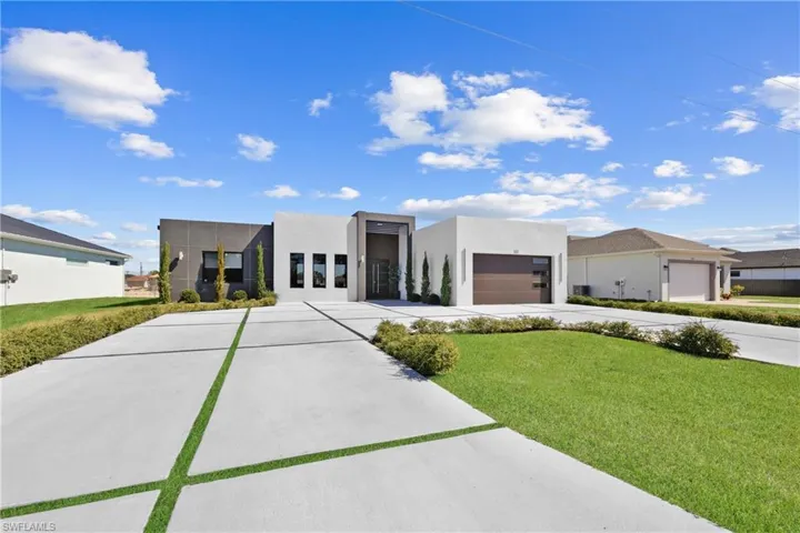 Modern home with driveway, stucco siding, an attached garage, and a front yard