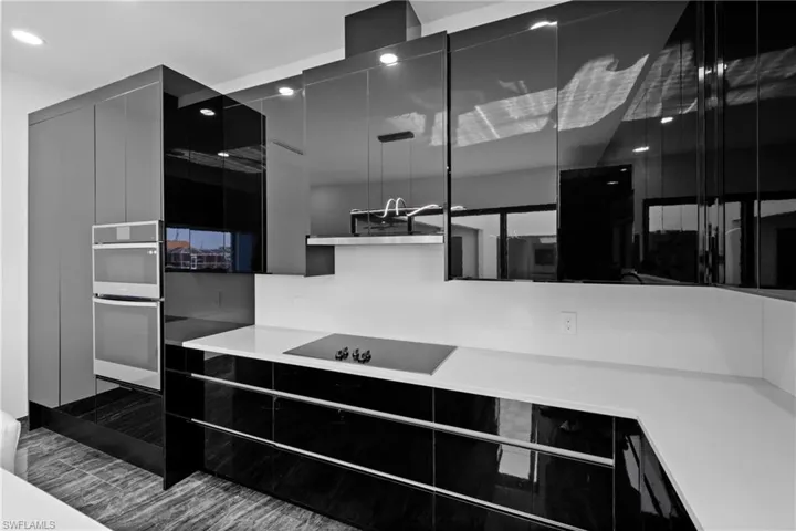 Kitchen featuring black electric cooktop, modern cabinets, dark cabinets, stainless steel double oven, and recessed lighting
