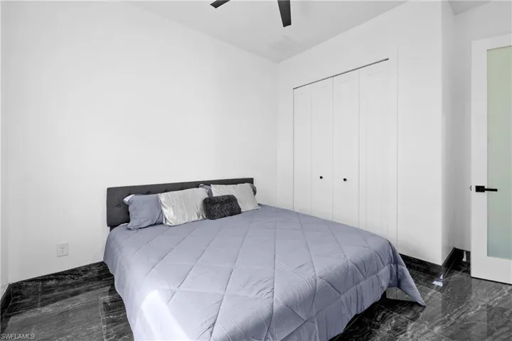Bedroom with marble finish floors, a closet, and a ceiling fan