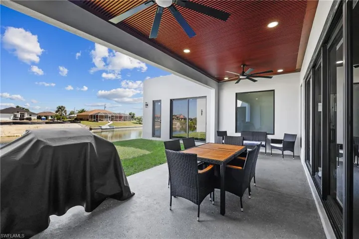 View of patio / terrace with ceiling fan, a water view, grilling area, and outdoor dining area