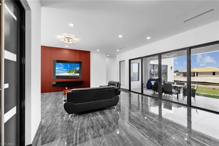 Living area featuring recessed lighting, marble tiled floors, an accent wall, and french doors