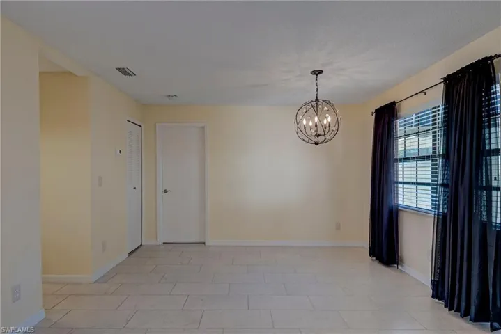 Unfurnished room with a chandelier and light tile patterned floors