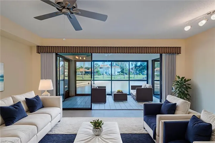 Living area with ceiling fan and tile patterned floors. Staged Image