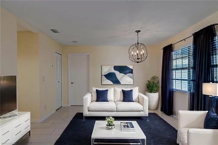 Living area featuring light tile pattern floors and a chandelier. Staged image
