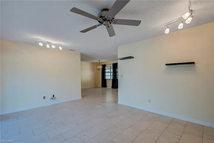 Unfurnished room with track lighting, a textured ceiling, a chandelier, and a ceiling fan