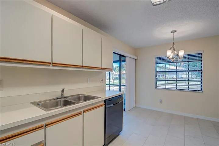 Kitchen featuring light countertops, white cabinetry, dishwasher, a textured ceiling, and pendant lighting