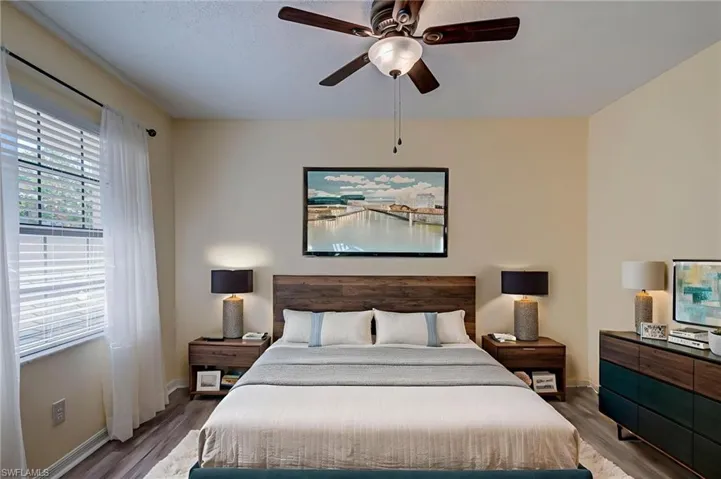Bedroom with dark wood finished floors and a ceiling fan. Staged image