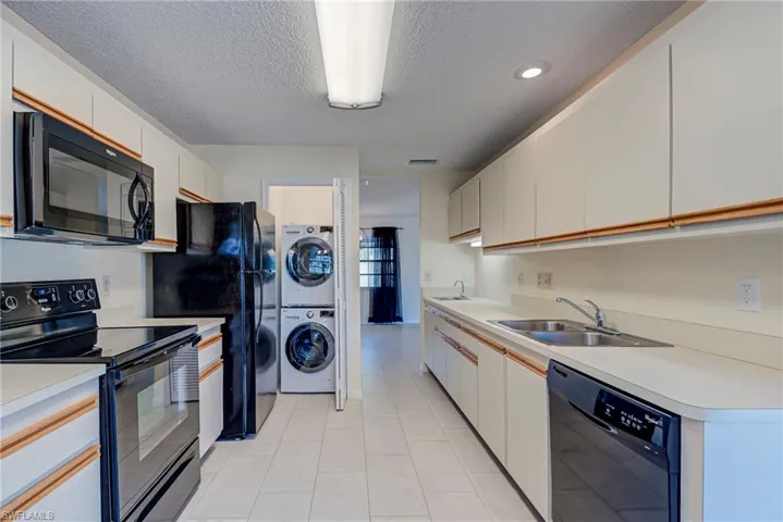 Kitchen featuring black appliances, a textured ceiling, light countertops, and white cabinets