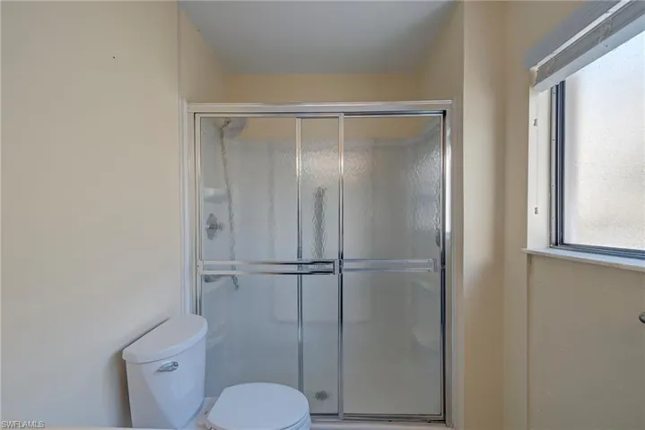 Full bath featuring a shower stall and toilet