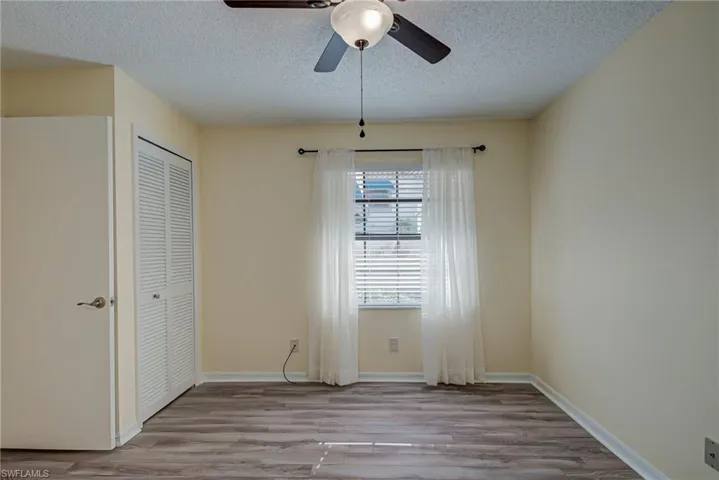 Unfurnished bedroom with wood finished floors, a textured ceiling, a closet, and ceiling fan