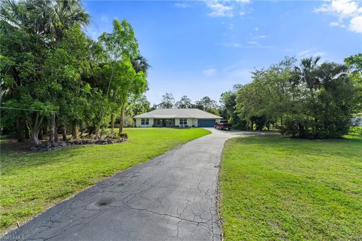 View of front of home featuring aphalt driveway and a front lawn