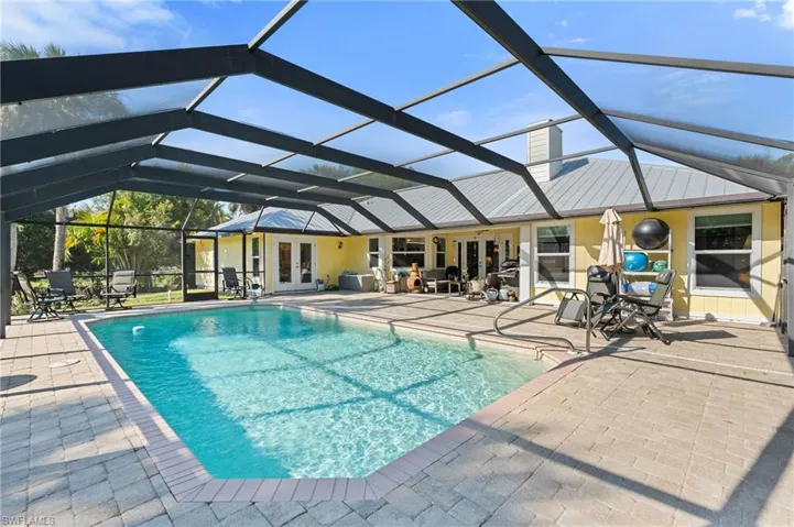 Back of house with a patio, a yard, glass enclosure, an outdoor pool, and a chimney