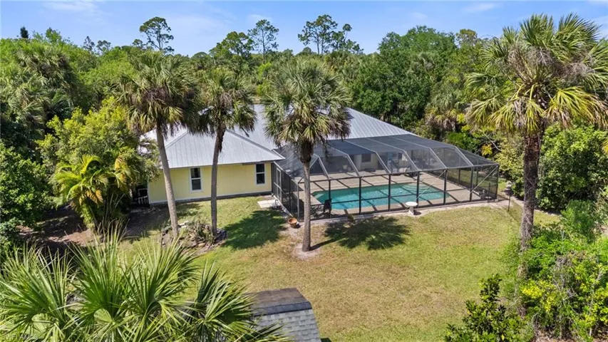 Single story home with aphalt driveway, metal roof, a garage, and a front lawn