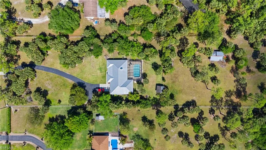 Ranch-style house with a front lawn, concrete driveway, a chimney, metal roof, and an attached garage