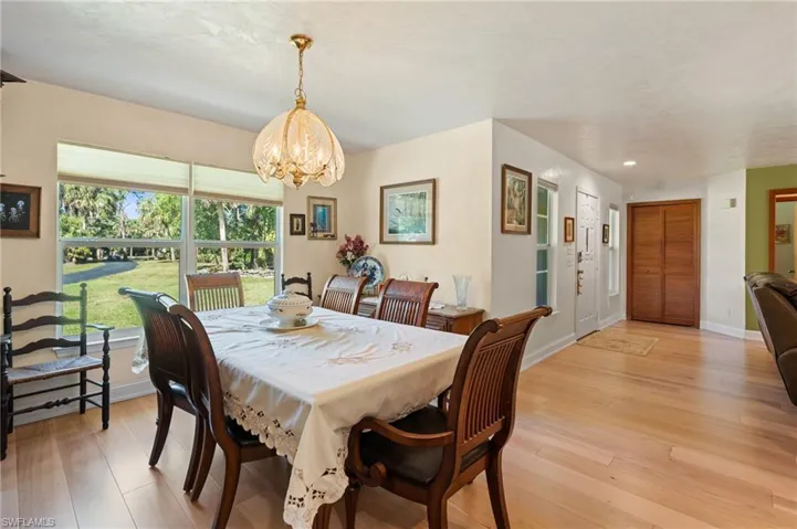 Dining space with baseboards, a chandelier, and light wood finished floors