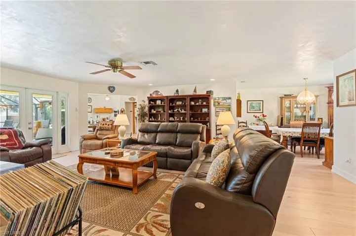 Living area featuring light wood-type flooring, visible vents, a tiled fireplace, baseboards, and ceiling fan