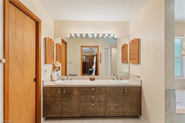 Bedroom with a ceiling fan, baseboards, visible vents, ensuite bath, and light wood-type flooring