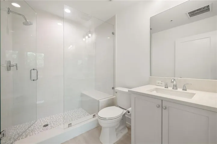 Full bath with visible vents, toilet, vanity, and a stall shower