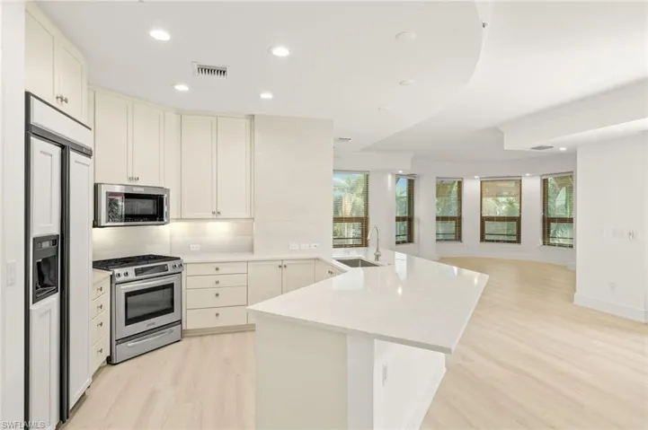 Kitchen with a sink, light wood finished floors, appliances with stainless steel finishes, a peninsula, and visible vents