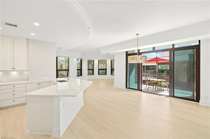 Kitchen featuring light countertops, a sink, open floor plan, light wood-type flooring, and white cabinets