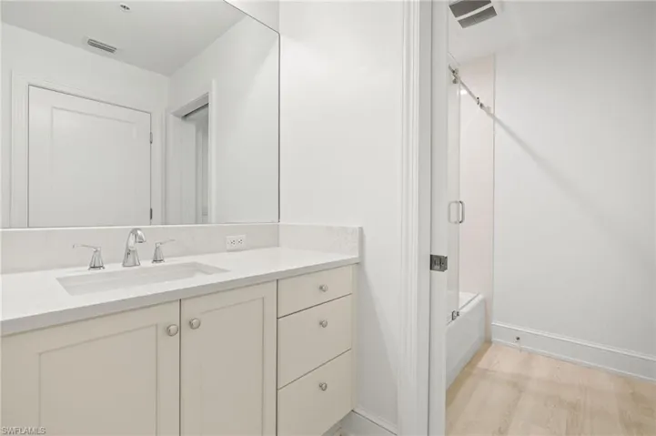 Bathroom featuring vanity, baseboards, washtub / shower combination, and visible vents