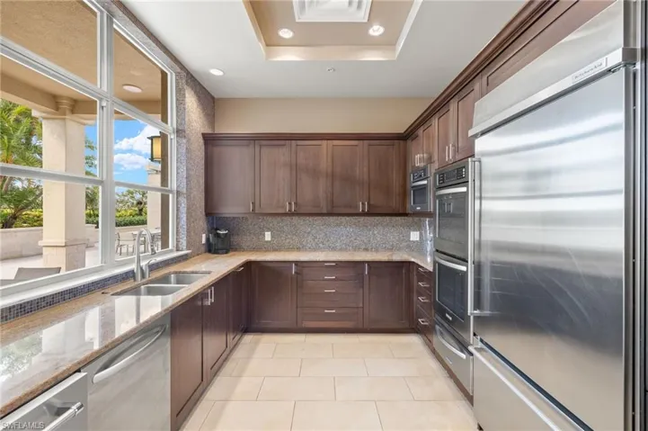 Kitchen featuring tasteful backsplash, recessed lighting, stainless steel appliances, a sink, and light stone counters