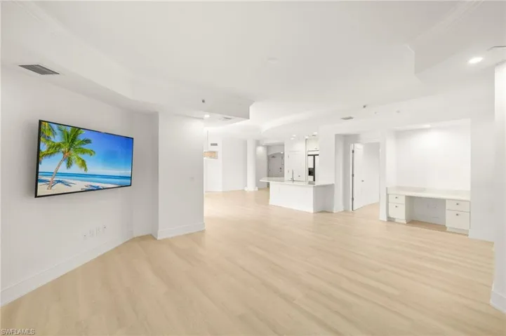 Unfurnished living room with baseboards, ornamental molding, visible vents, and light wood finished floors