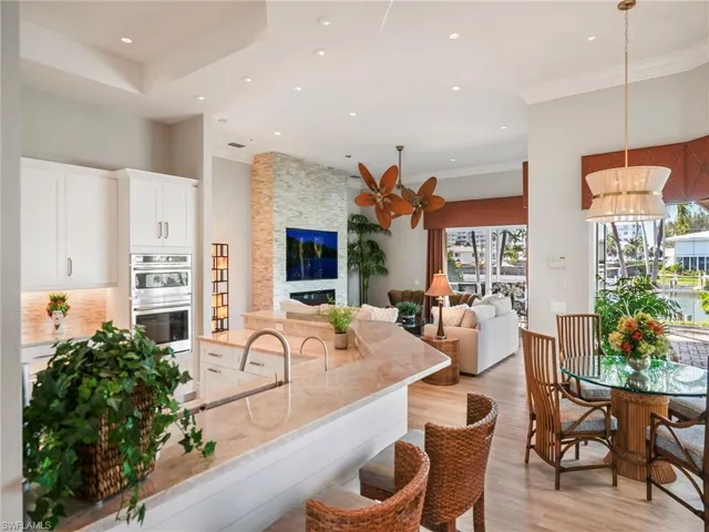 Kitchen with white cabinetry, light wood-style flooring, light stone counters, recessed lighting, and a stone fireplace