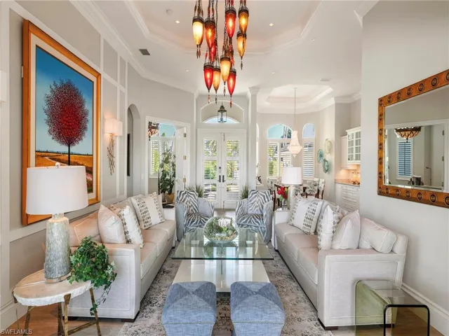 Living area with a raised ceiling, french doors, arched walkways, crown molding, and wood finished floors