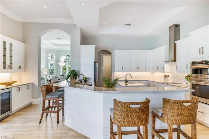 Kitchen with a kitchen bar, arched walkways, white cabinetry, and ornamental molding
