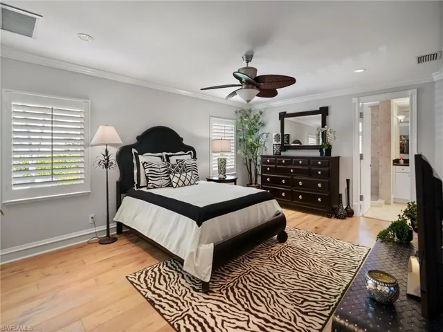 Bedroom featuring light wood-type flooring, ornamental molding, and a ceiling fan