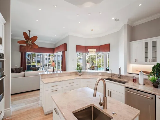 Kitchen with white cabinetry, glass insert cabinets, stainless steel appliances, open floor plan, and pendant lighting