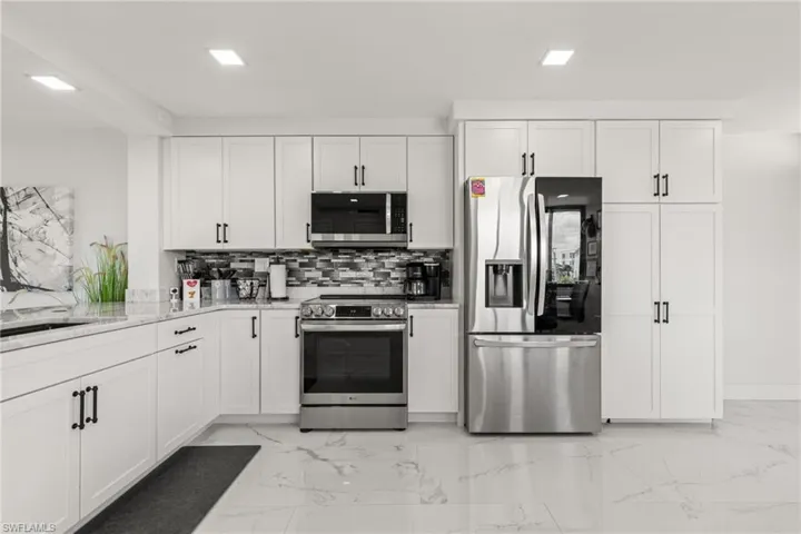 Kitchen featuring white cabinets, appliances with stainless steel finishes, tasteful backsplash, and sink