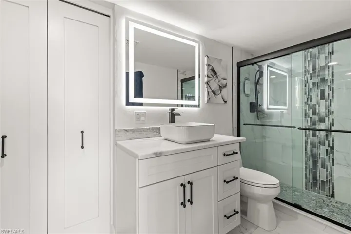 Bathroom featuring vanity, toilet, and a shower with door