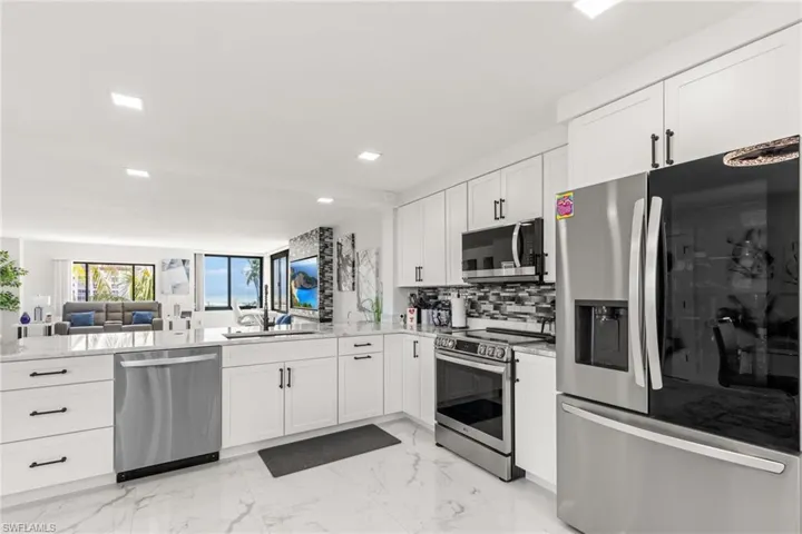 Kitchen with tasteful backsplash, stainless steel appliances, kitchen peninsula, and white cabinetry