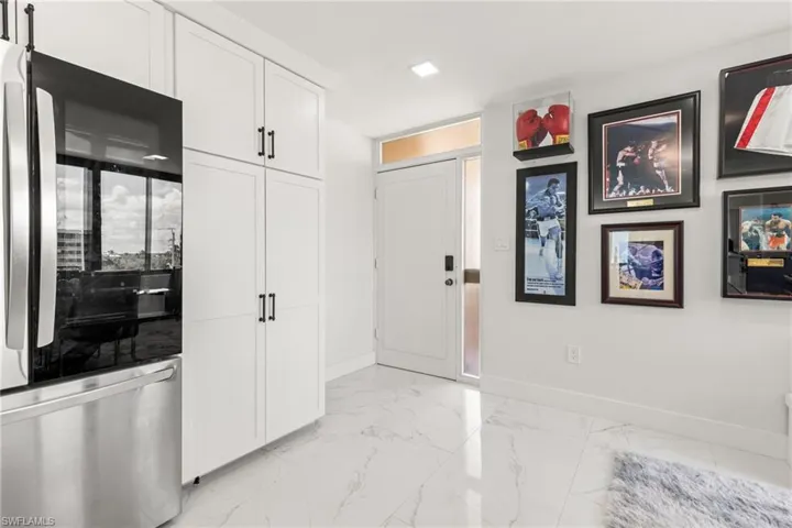 Kitchen featuring stainless steel fridge and white cabinets