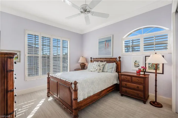 Carpeted Guest  bedroom 1 with ceiling fan and ornamental molding