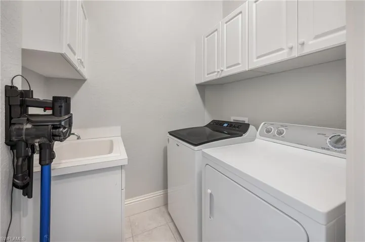 Laundry room featuring cabinets, light tile patterned floors, and washing machine and clothes dryer