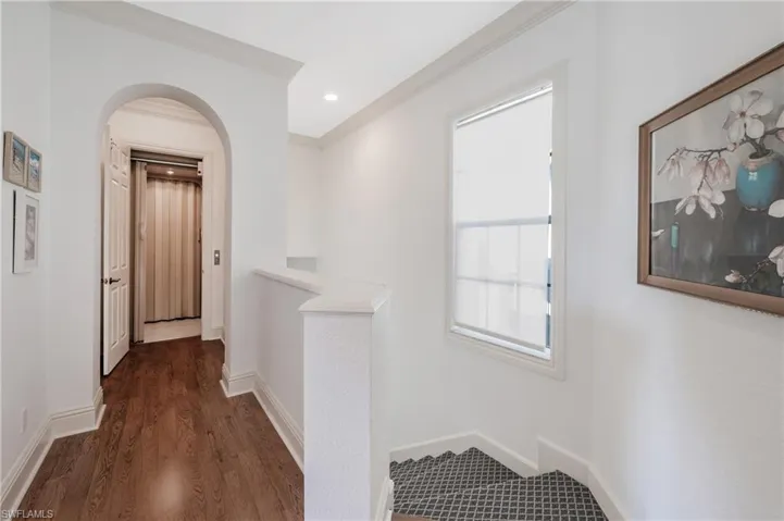 Hall with laminate flooring and ornamental molding leading to private elevator