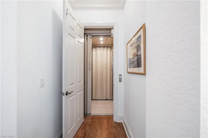 Hall to elevator with ornamental molding and laminate floors