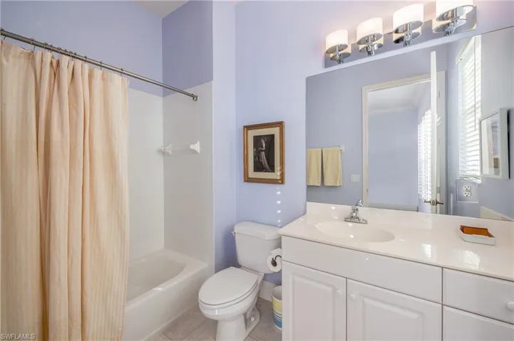 Full Guest bathroom featuring tile patterned flooring, vanity, toilet, and shower / bathtub combination with curtain