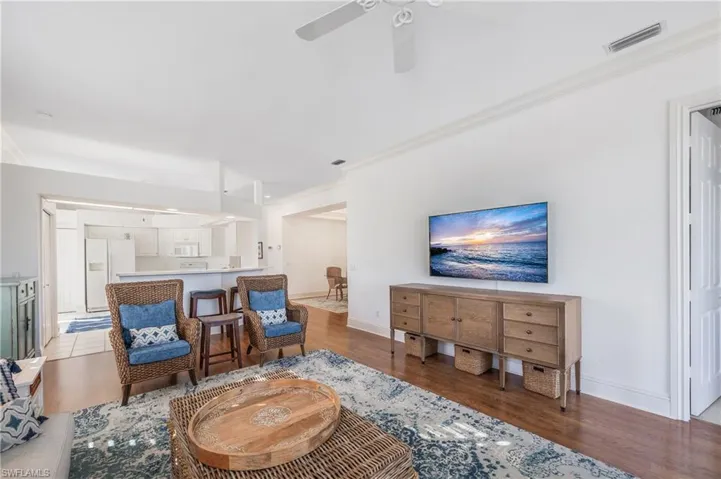 Living room featuring laminate flooring, ornamental molding, and ceiling fan