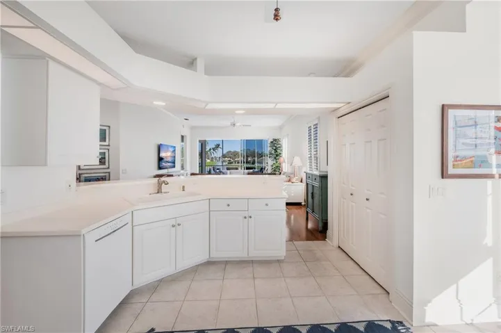 Kitchen with light tile patterned floors, sink, dishwasher, white cabinets, and kitchen peninsula