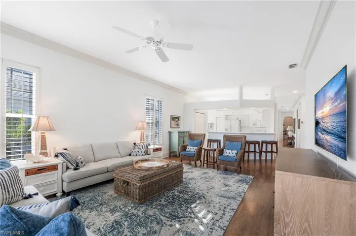 Living room featuring plantation shutters, crown molding, ceiling fan, and Laminate flooring