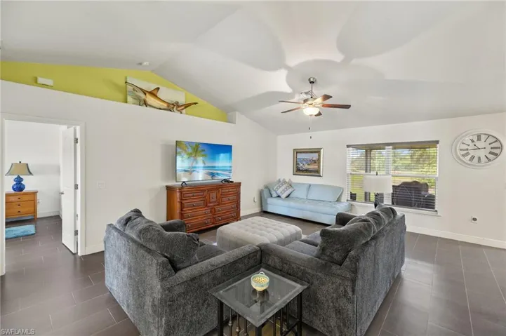 Living room featuring lofted ceiling, baseboards, and ceiling fan