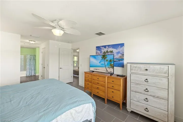 Bedroom with a ceiling fan, dark tile patterned flooring, and ensuite bath